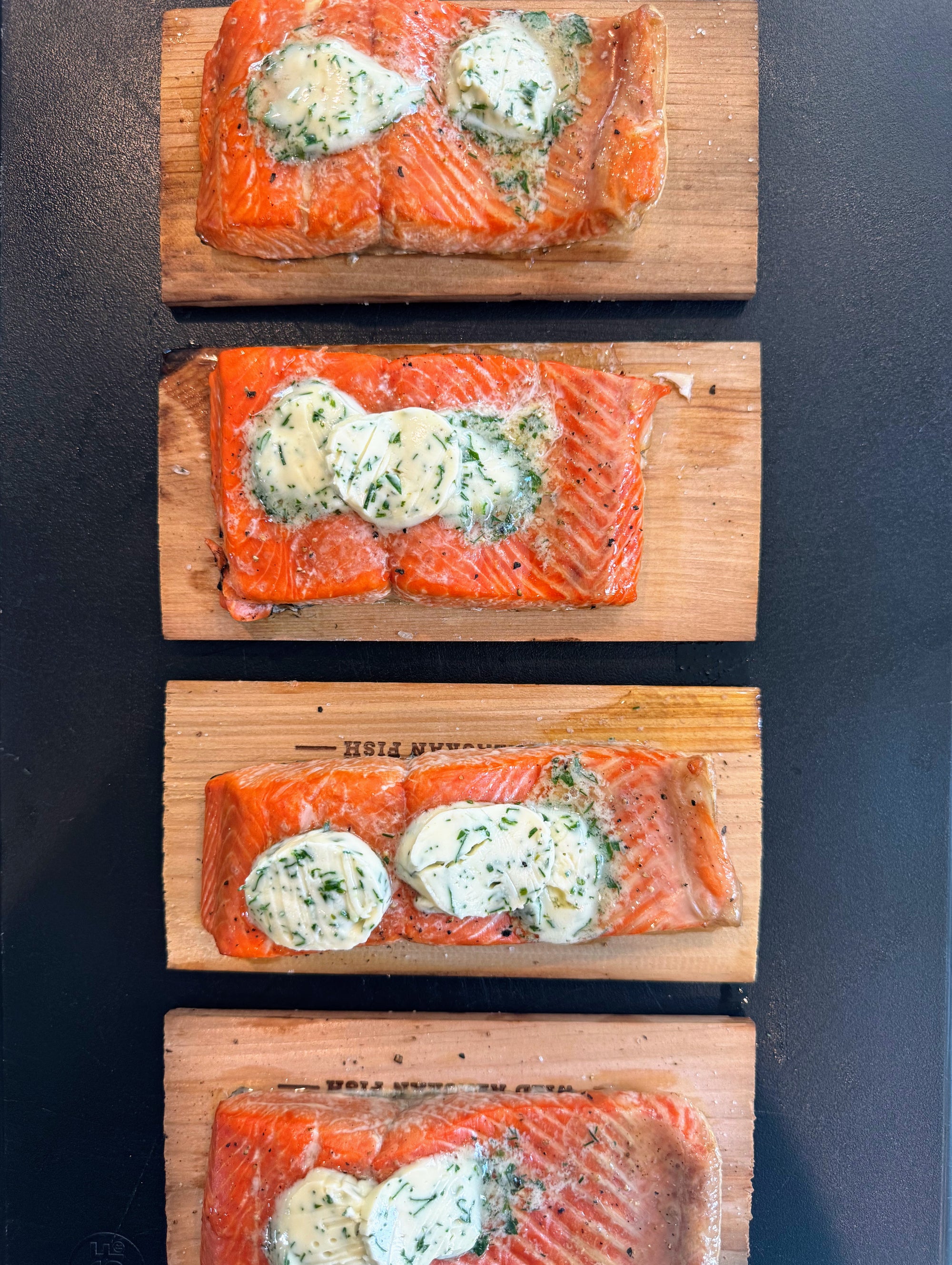 Salmon fillets topped with a creamy herb mixture on cedar planks.
