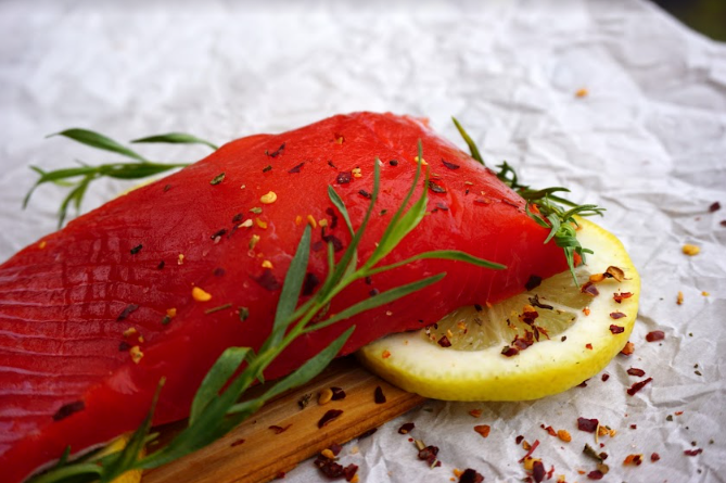 Sea Sea wild caught copper river salmon Fillet resting on herbs and a lemon slice