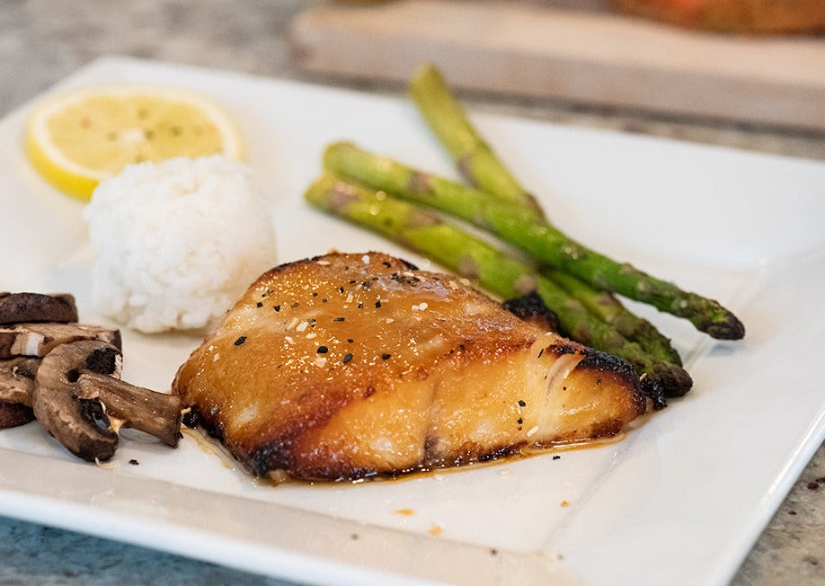 Cooked Wild caught Alaskan Marinated misoyaki sablefish fillet on a plate with seared veggies