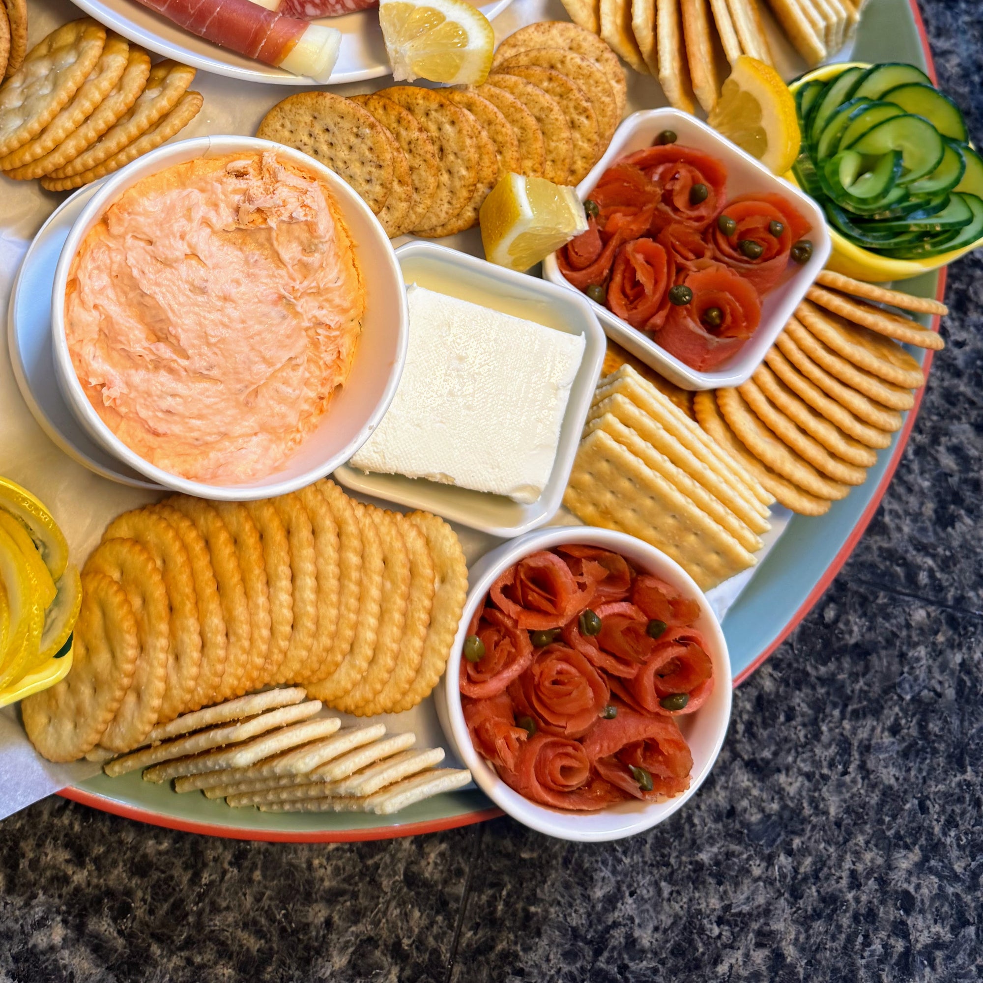 Assorted appetizers, including smoked salmon lox, crackers, and vegetables on a platter.