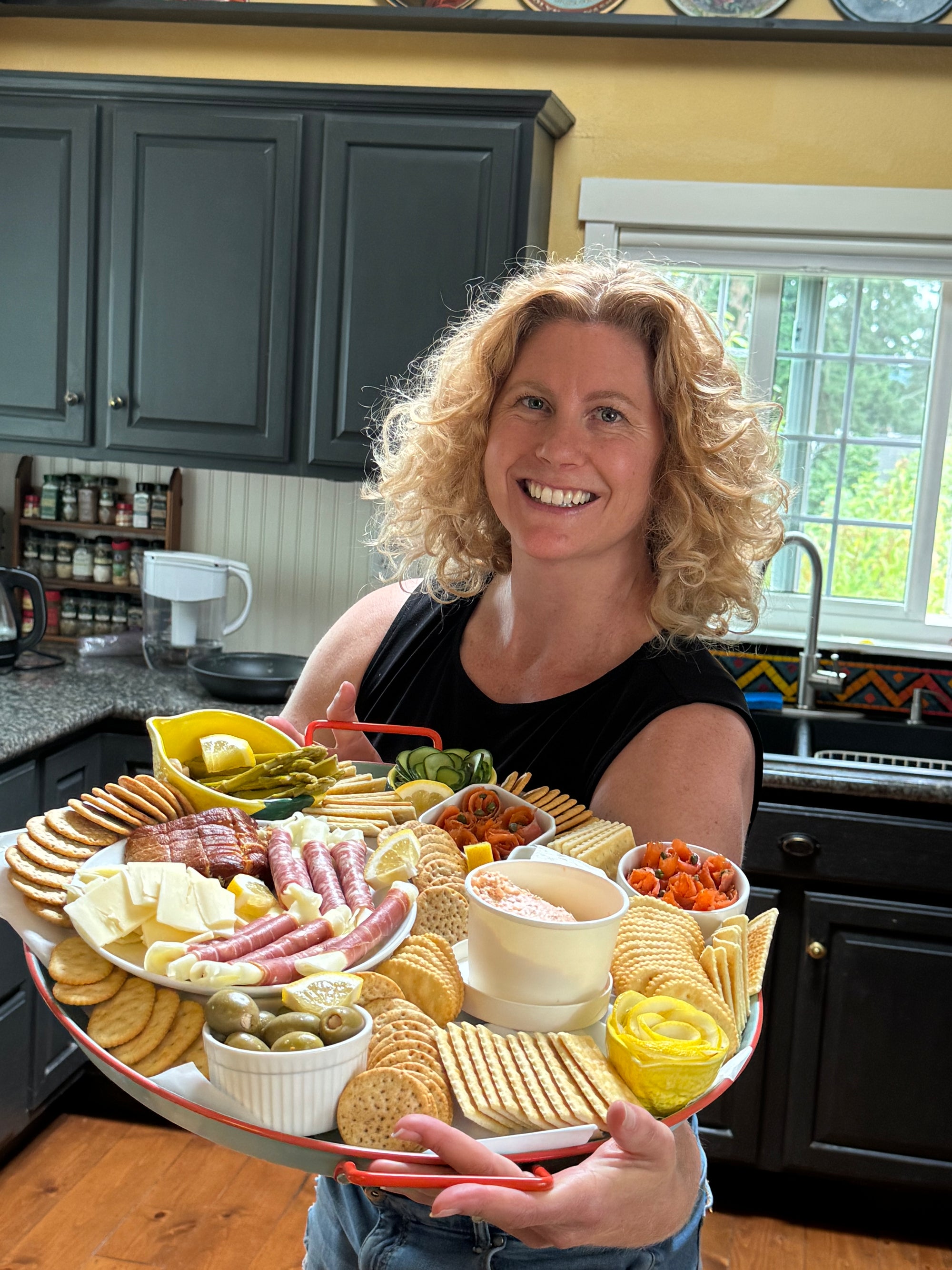Sena holding a large charcuterie board in a kitchen