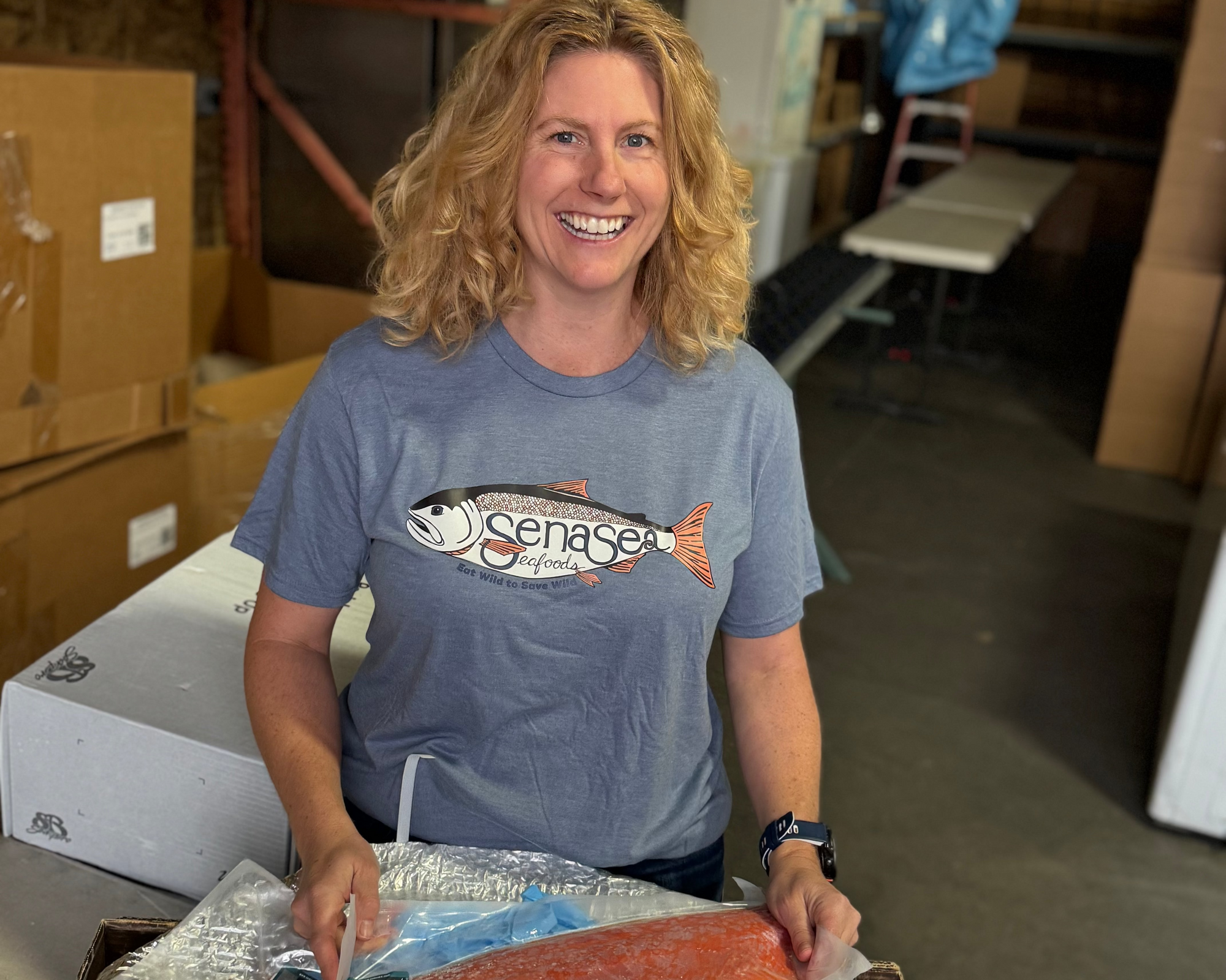 Sena wearing a Sena Sea teeshirt, holding salmon