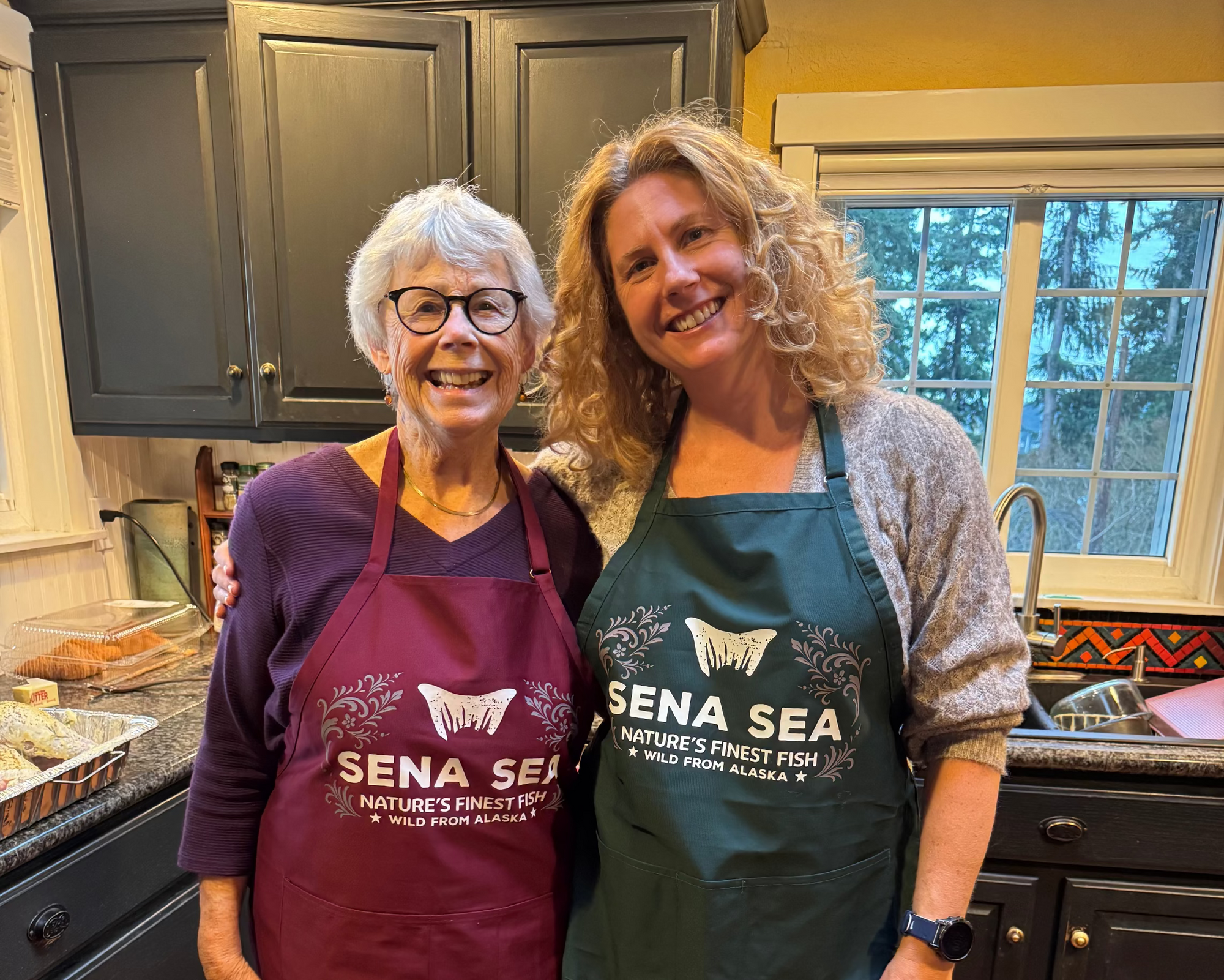 Two women wearing aprons in a kitchen