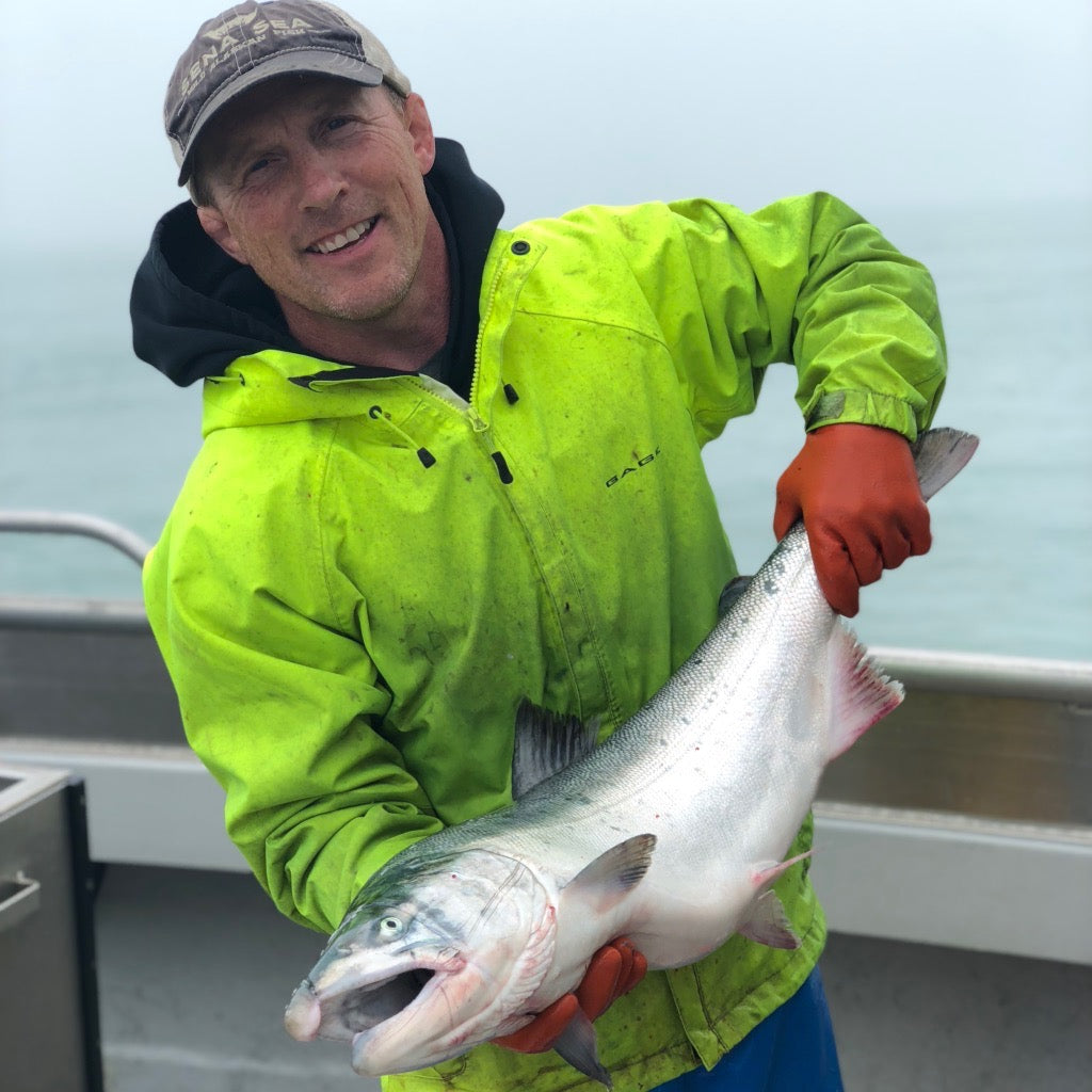 Rich Wheeler, Sena's Husband and main fisherman holding a just caught Copper River Salmon on their fishing boat in Alaska