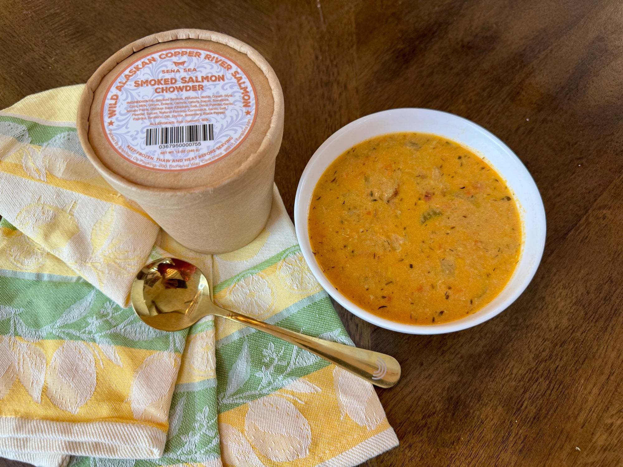  bowl ofsmoked salmon chowder with a spoon and container on a wooden surface