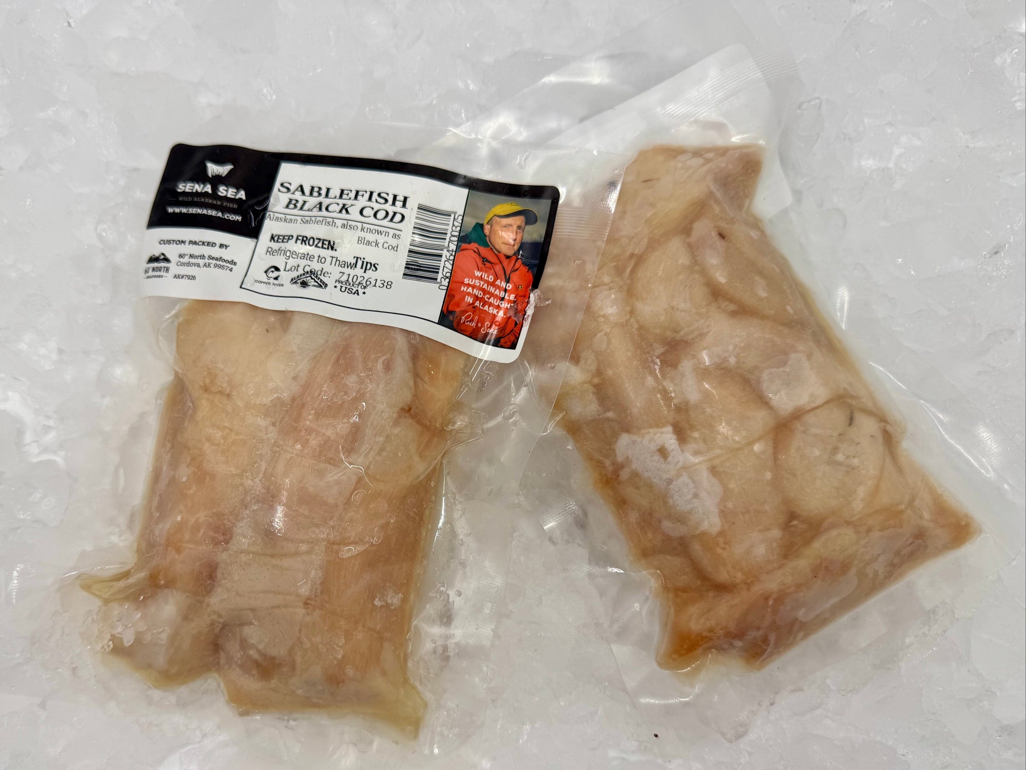 Two vacuum-sealed packages of raw Sablefish (Black Cod) tips on a bed of ice, with a label from Sena Sea.