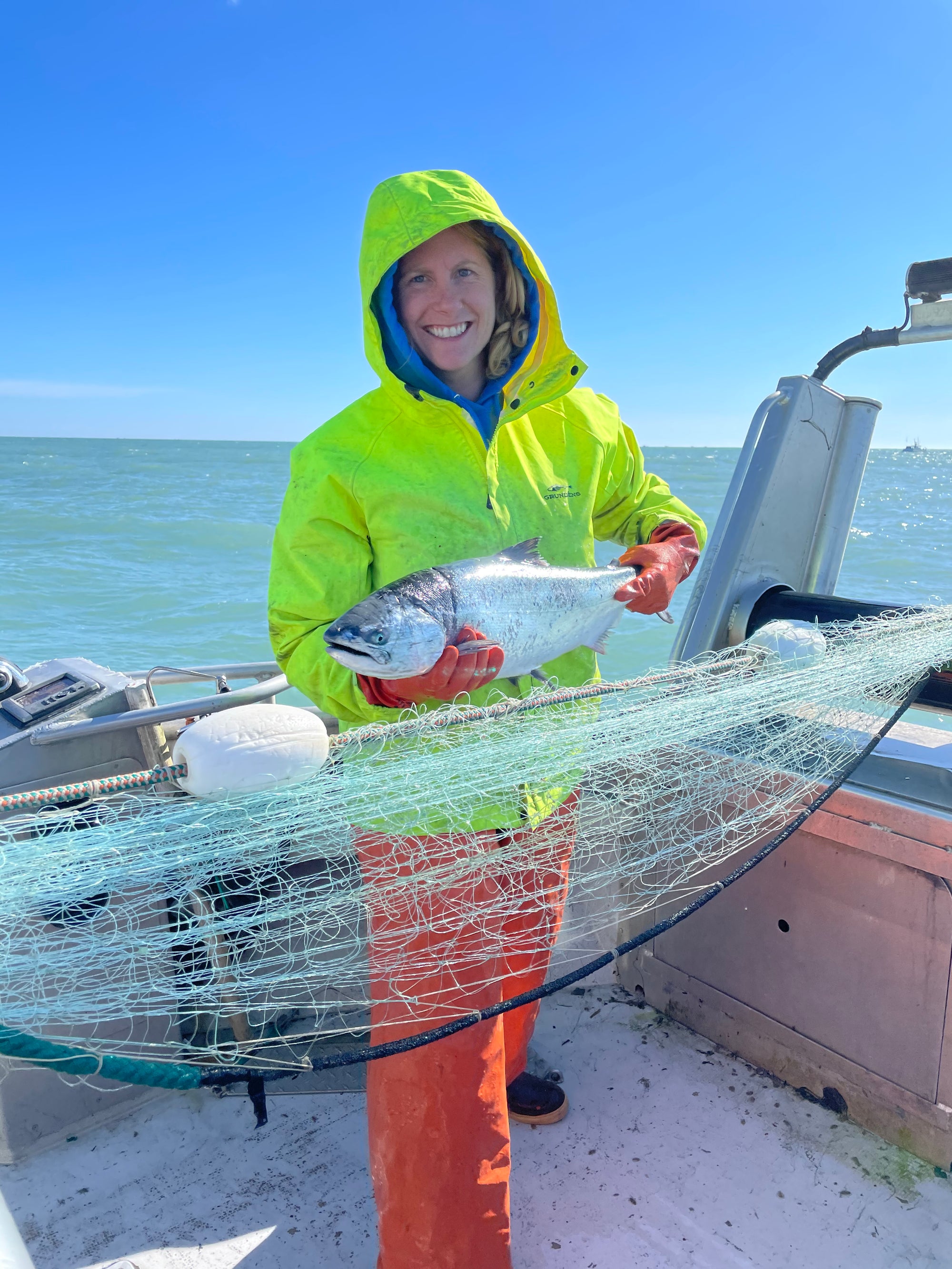 Sena holding a fish on a boat with a clear blue sky